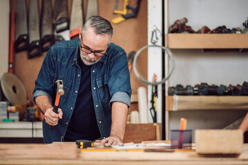 Professional senior cauasian man working woodworking handmade with tools in wood workshop, Timber factory industry.