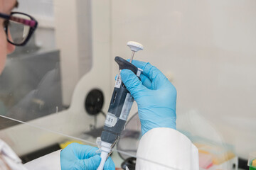 Lab technician wearing blue nitril gloves setting a micropipet to the correct volume.