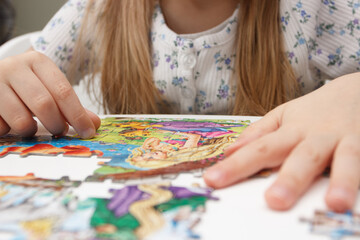 Little child picks up picture from pieces of puzzles