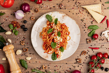 Spaghetti with Tomato Sauce, Cheese and Basil on Rustic Plate.
Classic spaghetti in red sauce topped with grated cheese and fresh basil, served on a white plate with rustic Italian ingredients around.