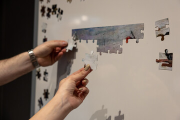 Shuffled magnetic puzzle pieces on a magnet white board waiting to be put together.