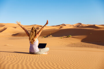 Fototapeta na wymiar Freelancer woman work on computer in the sahara desert- work, freelance, booking or travel concept