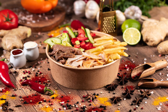 Doner Kebab Bowl with Mixed Meat, Fries, and Fresh Vegetables.
Colorful doner bowl featuring a mix of sliced chicken and beef, served with French fries, lettuce, tomatoes, cucumbers, and red peppers. 