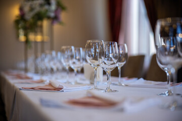 Beautifully laid tables with glasses and appliances at morning in restaurant set up for a wedding. High quality photo