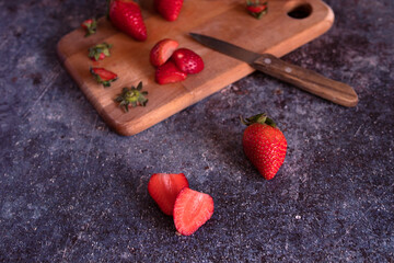 Wooden board with strawberries and a knife in a kitchen.