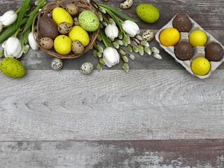  Ostereier mit weißen Tulpen und Weidenkätzchen  auf einem Holzhintergrund mit Platz für Text.