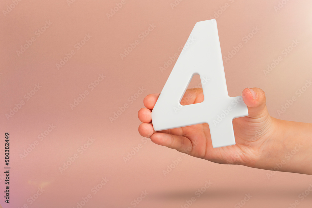 Aufkleber number four in hand. hand holding white number 4 on red background with copy space. concept with num