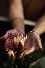 Mehndi adorns the women's hands with a beautiful flower design.Vesak day, Buddhist lent day, Buddha's birthday worshiping concept with woman's hands holding water lilly or lotus flower 