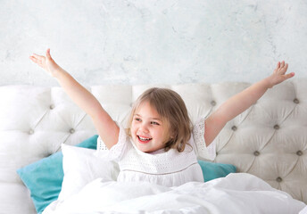 Child girl in a bed happy face. Little girl sensual portrait. Good morning. Toddler in a good mood. Good sleep. Kid in bedroom.