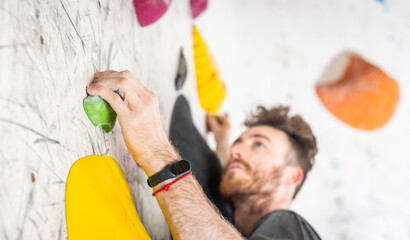 Young climber climbing on the boulder wall indoor, rear view, concept of extreme sports and...