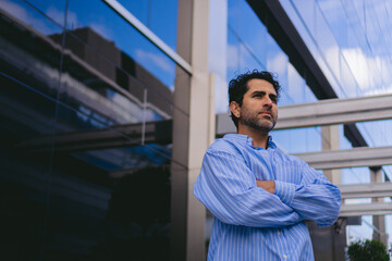 Fototapeta premium Serious middle-aged Latin man with his arms folded outside a business district. Copy space.