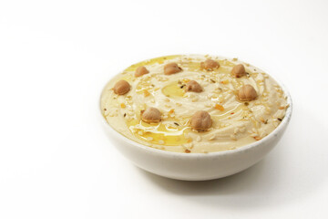 Classic Hummus on a white background in a plate topped with chickpeas and sesame seeds, oil and spices. Culinary and food menu photo. Eastern or Mediterranean cuisine.