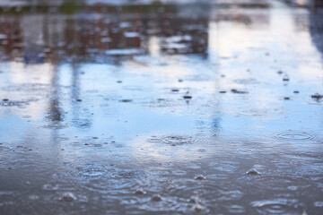 Heavy rain falling on the asphalt, puddles with splashes from drops..