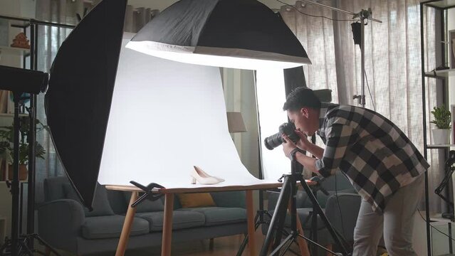 Asian Male Photographer Being Tired Taking Photos Of Women'S Shoes In Home Studio 
