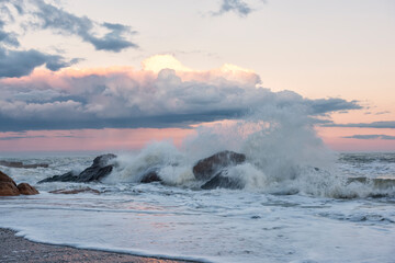 Seascape long exposure. Waves bending around rocks in the water against a dramatic sky.
