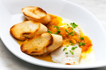 white fish with tomato sauce and roasted baguette slices