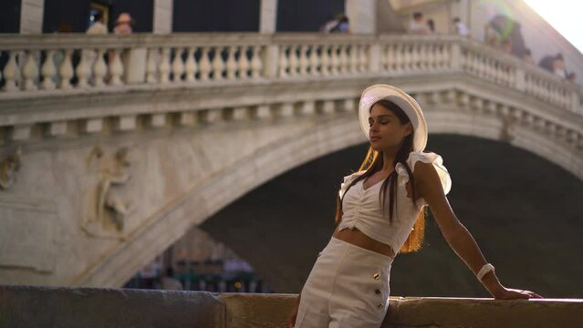 Young girl traveler in white clothes relax standing by Bridge in Venice Italy, Sunset summer time