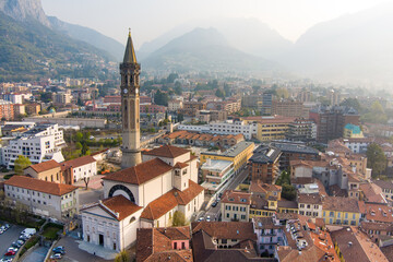 Fototapeta na wymiar Foggy aerial sunrise cityscape of Lecco town on spring day. Picturesque waterfront of Lecco town located between famous Lake Como and scenic Bergamo Alps mountains.