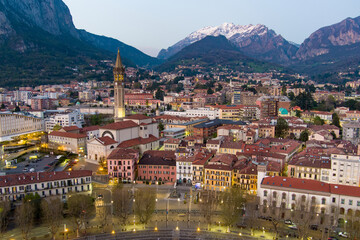Fototapeta na wymiar Stunning aerial cityscape of Lecco town on spring evening. Picturesque waterfront of Lecco town located between famous Lake Como and scenic Bergamo Alps mountains.