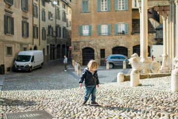 Cute toddler boy walking down the street of Bergamo. Little child having fun exploring in Citta Alta, upper district of Bergamo. Bergamo, Italy.