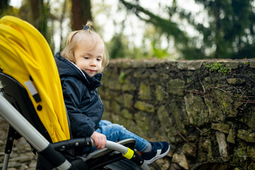 Sweet toddler boy sitting in a stroller outdoors. Little child in pram. Infant kid in pushchair....