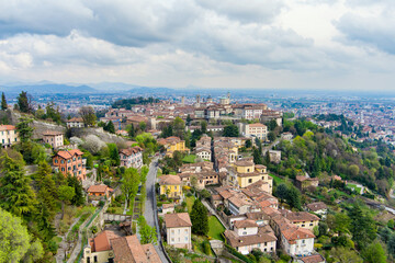 Scenic aerial view of Bergamo city. Flying over Citta Alta, town's upper district, known by cobblestone streets and encircled by Venetian walls. Bergamo, Lombardy, Italy.
