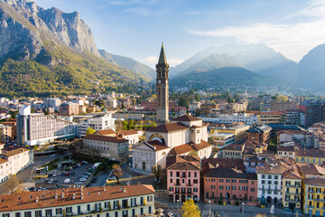 Fototapeta na wymiar Sunny aerial cityscape of Lecco town on spring morning. Picturesque waterfront of Lecco town located between famous Lake Como and scenic Bergamo Alps mountains.