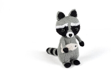 knitted raccoon with fish in hands on white background © Irina
