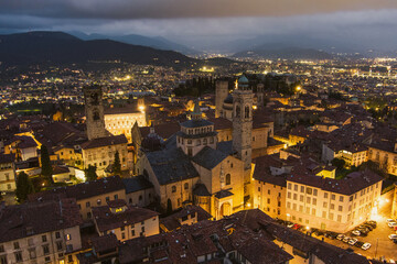 Scenic aerial view of Bergamo city northeast of Milan, on cloudy evening. Flying over Citta Alta, town's upper district encircled by Venetian walls. Bergamo, Italy.