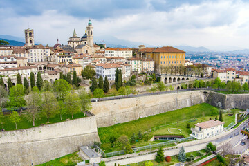 Fototapeta na wymiar Scenic aerial view of Bergamo city. Flying over Citta Alta, town's upper district, known by cobblestone streets and encircled by Venetian walls. Bergamo, Lombardy, Italy.