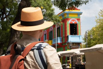 Caucasian young man, father carrying little newborn baby in carrier,family traveling, going sightseeing in center of La Boca quarter, Buenos Aires, Argentine, looking at bright colourful buildings.