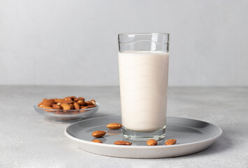 Fresh almond milk in tall glass on gray plate, Healthy vegan milk replacer