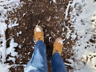 Füße mit Stiefeln beim Wandern im Wald im Winter bei leichtem Schnee