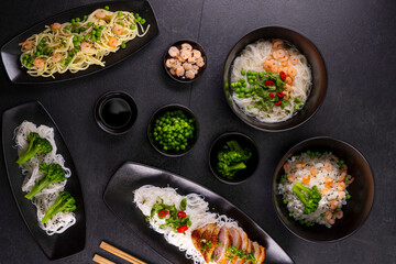 Various dishes of Asian cuisine with different types noodles and rice with shrimp, duck, vegetables and black sesame