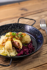 dumpllings filled with smoked meat served with red and white cabbage