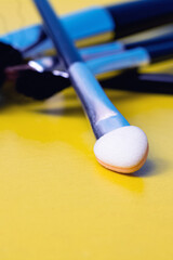 Makeup brushes on a yellow background closeup