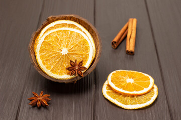 Star anise and dried orange slices in coconut shell. Cinnamon sticks on the table.