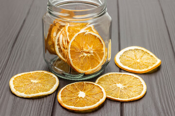 Dry orange slices on the table and in a glass jar.