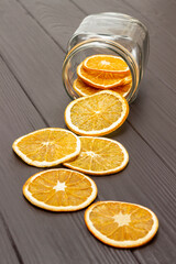 Dry orange slices are scattered from a glass jar on the table.