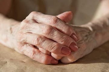 Foto op Plexiglas Oude deur the hands of an elderly woman lie on the table folded one into the other