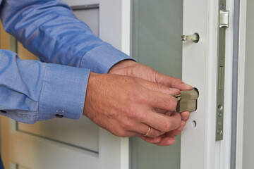 installing a lock on a plastic door,a professional locksmith repairs a door in an office, door...