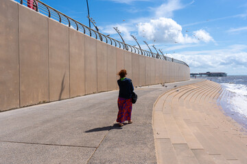 Woman standing by the sea at sunset. Woman walking on the beach by the sea