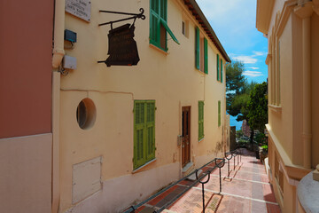 Small narrow street walk way alley leading to beach with simple wall and green window wooden shutters