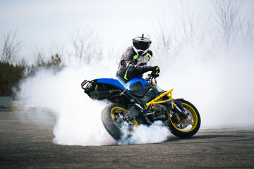 Biker performing a burnout with his stunt motorcycle and making a lot of smoke from rear wheel
