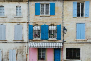 Old exterior vintage house in Italy with blue and pink window shutters