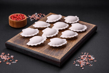 Raw frozen stuffed dumplings on a wooden cutting board