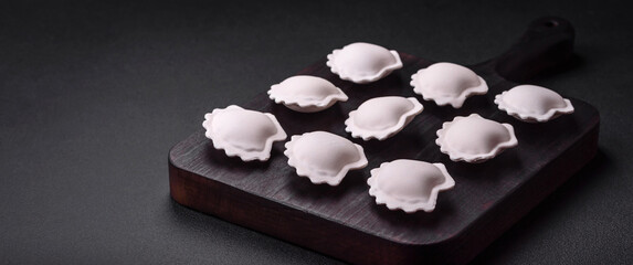 Raw frozen stuffed dumplings on a wooden cutting board