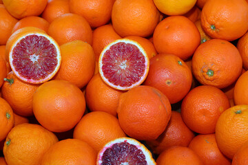 background of many ripe orange oranges and two halves open to see the juicy contents for sale at the greengrocer