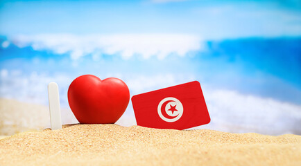 I love Tunisia. Flag of Tunisia on the beach with a red heart. vacation and travel concept. - obrazy, fototapety, plakaty