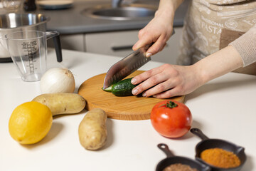 The girl is cutting vegetables, using a knife to chop carrots, onions, and peppers for a stir-fry or salad.